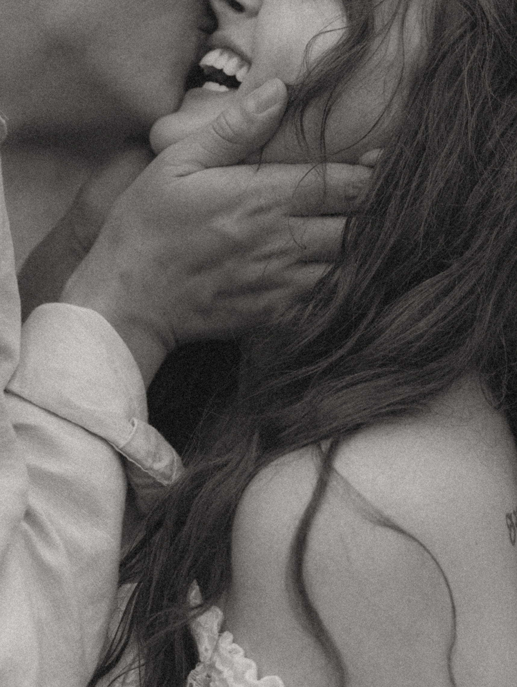 Black and white close-up of Dakota laughing as Rowdy cups her face in his hand