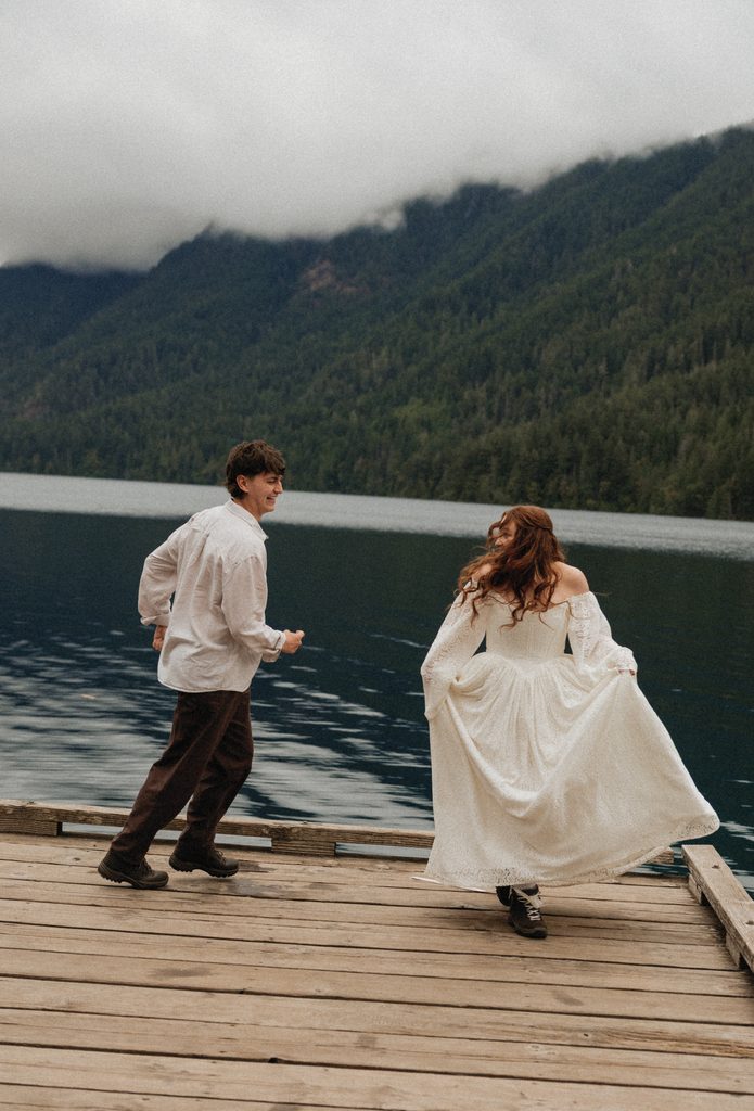 Dakota and Rowdy dancing across a wooden dock on Lake Crescent under low clouds