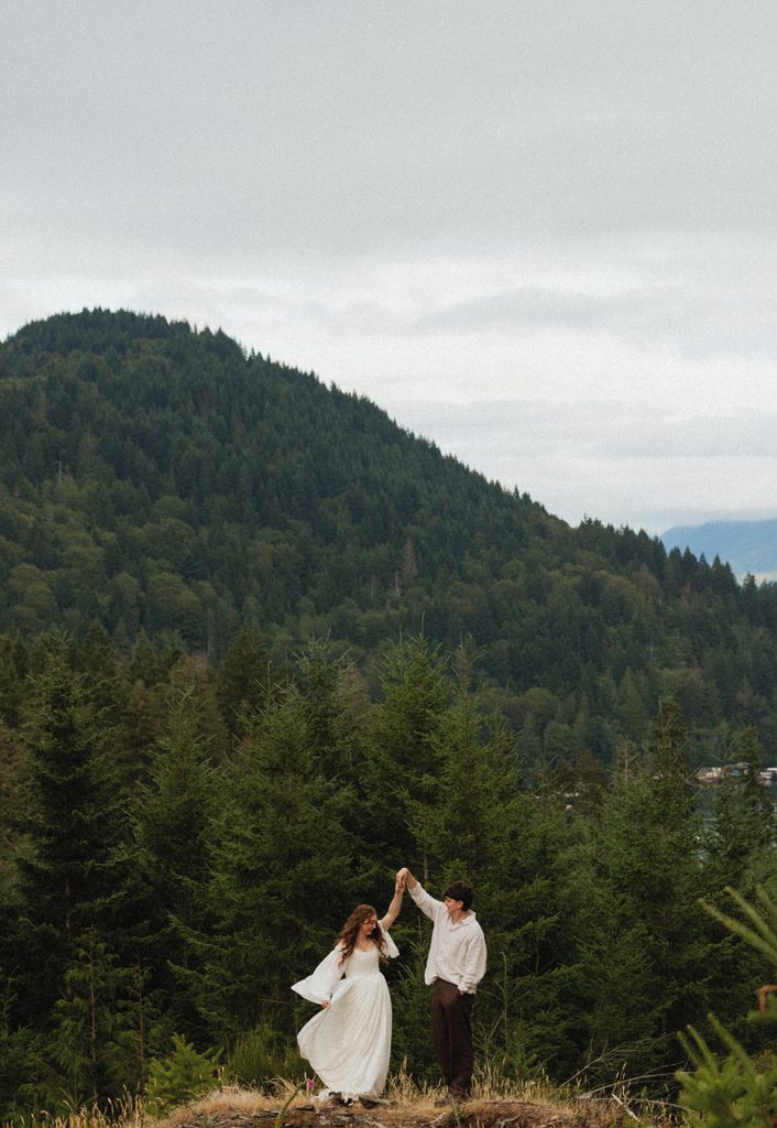 Rowdy twirls Dakota on a hilltop clearing with forested mountains rising behind them
