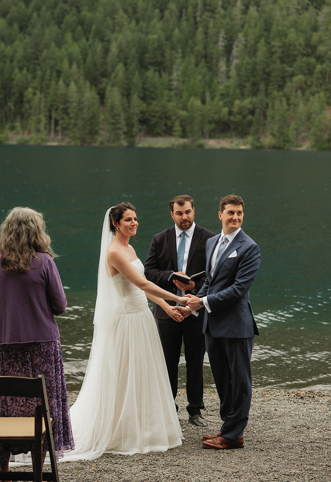 Beth and Jamie face their officiant during their ceremony on the shore of Lake Crescent